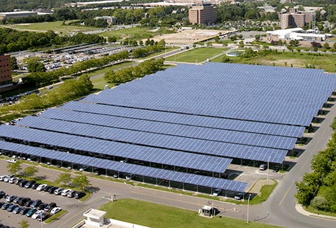 Solar panels are installed over parking spaces to maximize solar energy collection.