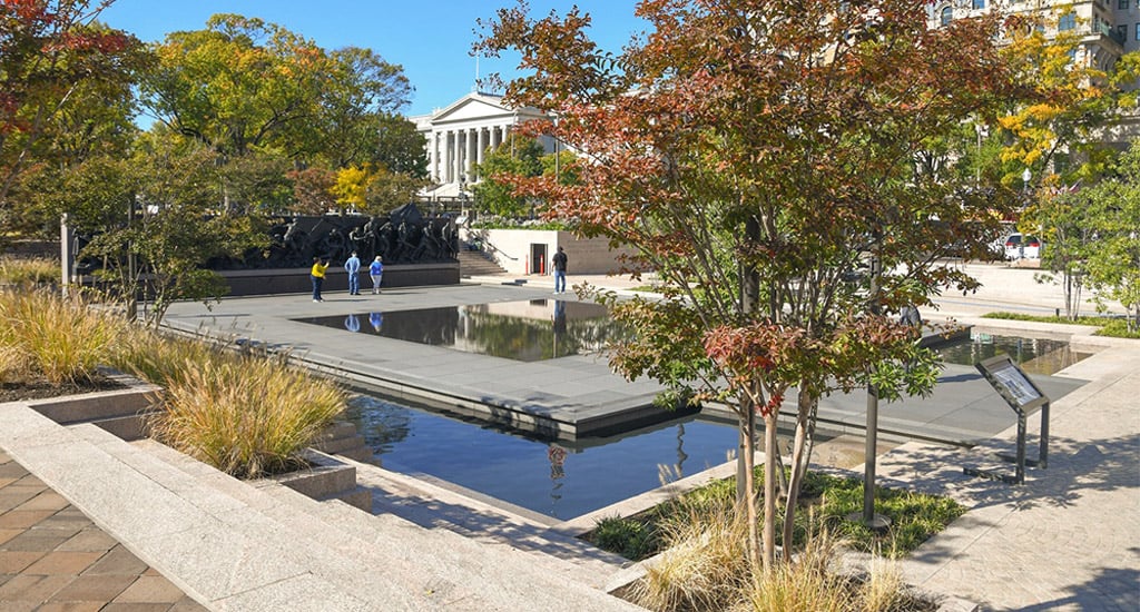 A sculpture of soldiers in an outdoor setting with water and vegetation.
