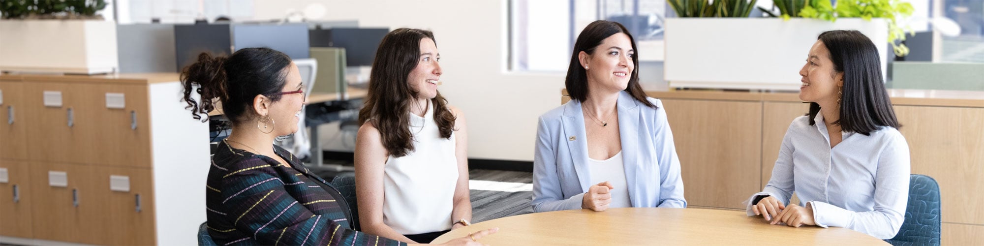 Four employees seated around a table in an office setting.