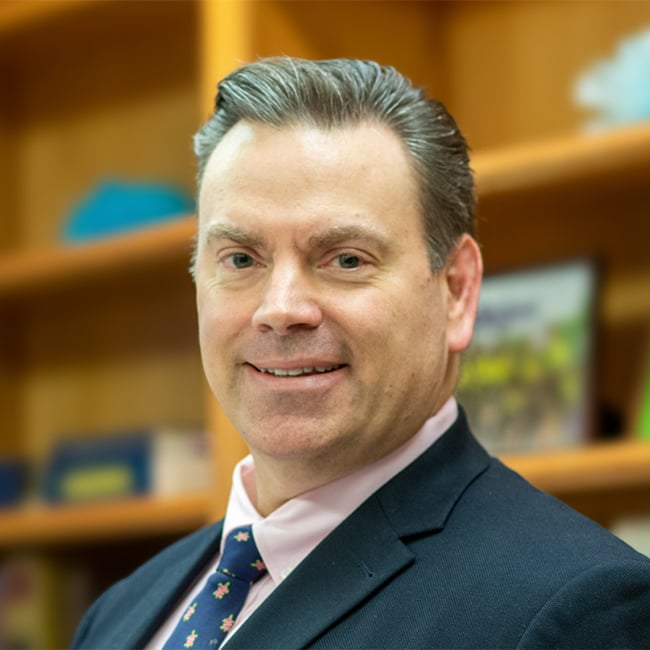 Brian Perry in the office wearing a dark blue suit and tie.