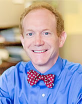 Chris smiling in a blue shirt and red bow tie.