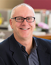 A man in a dark gray shirt with a black blazer.