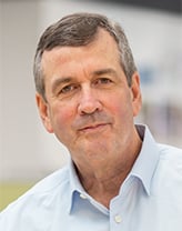 Daniel Faust stands in an office wearing a blue shirt.