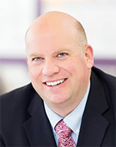 Man wearing a dark suit and tie in an office setting