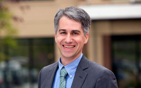 Man wearing gray suit and tie in outdoor setting