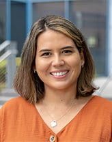 A woman with short brown hair wearing an orange shirt