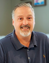 Richard Lewis in a navy blue polo shirt.