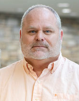 Headshot of Steve Yates wearing a button-down business shirt in an office setting.