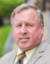 Thomas Donald smiling in a yellow shirt and oatmeal blazer.