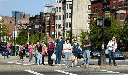 Pedestrians walk in a crosswalk in an urban environment.