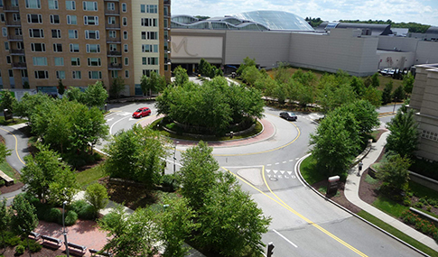 Landscaped access road and roundabout outside of a mixed-use development.