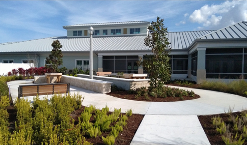 A garden, bench, and path in front of a one-story Veterans nursing home.