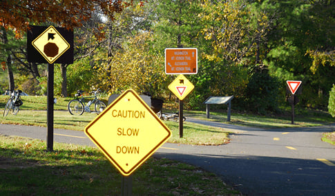 Multiple signs on a bike trail.