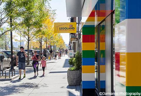 Visitors walk along the sidewalk near the Lego store at Assembly Row.