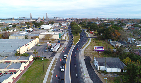 Aerial view of cars driving on Bay Street in Savannah with a large bridge over water in the background