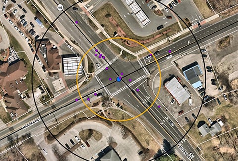 Aerial view of a pink three-way roundabout, showing the rooftops and rooftop parking lots of nearby buildings.