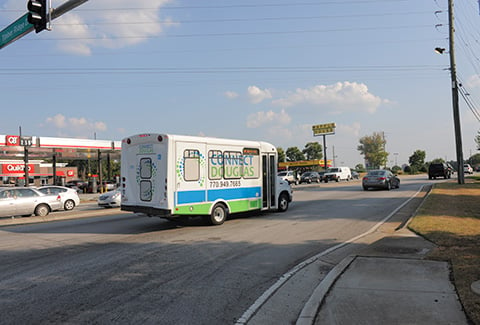 A fleet of small buses with Connect Douglas signage on the body of the vehicle