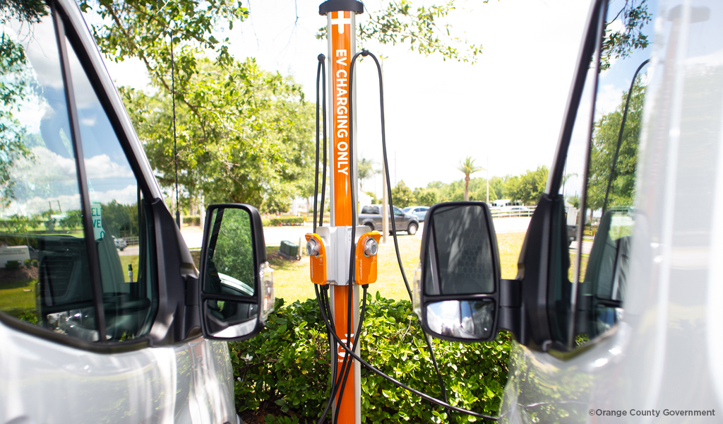 A EV charging station positioned between two autos.