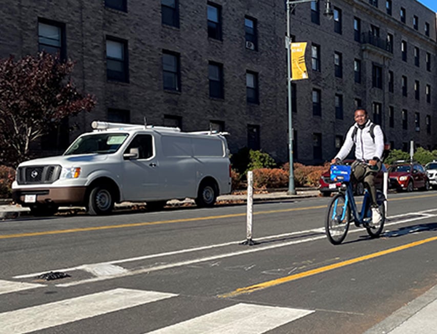 Bicyclist riding along a separated bicycle lane on an urban street.