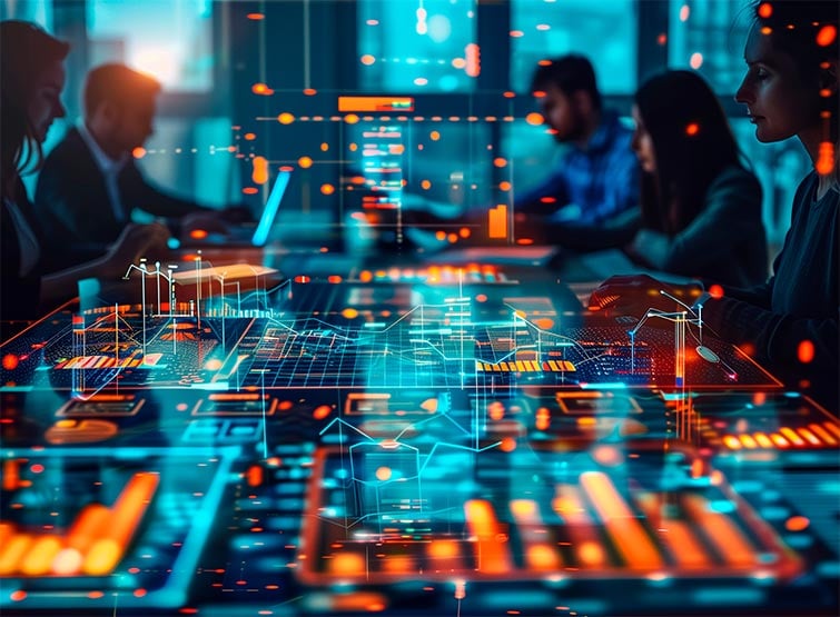 A team of people seated around a table looking at digital screens.