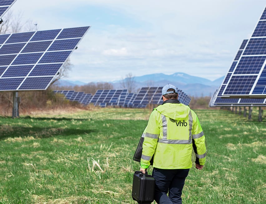 VHBer walking through a solar farm wearing a safety vest. 