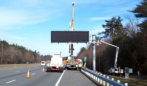 Crew installing an overhead digital messaging sign along highway.