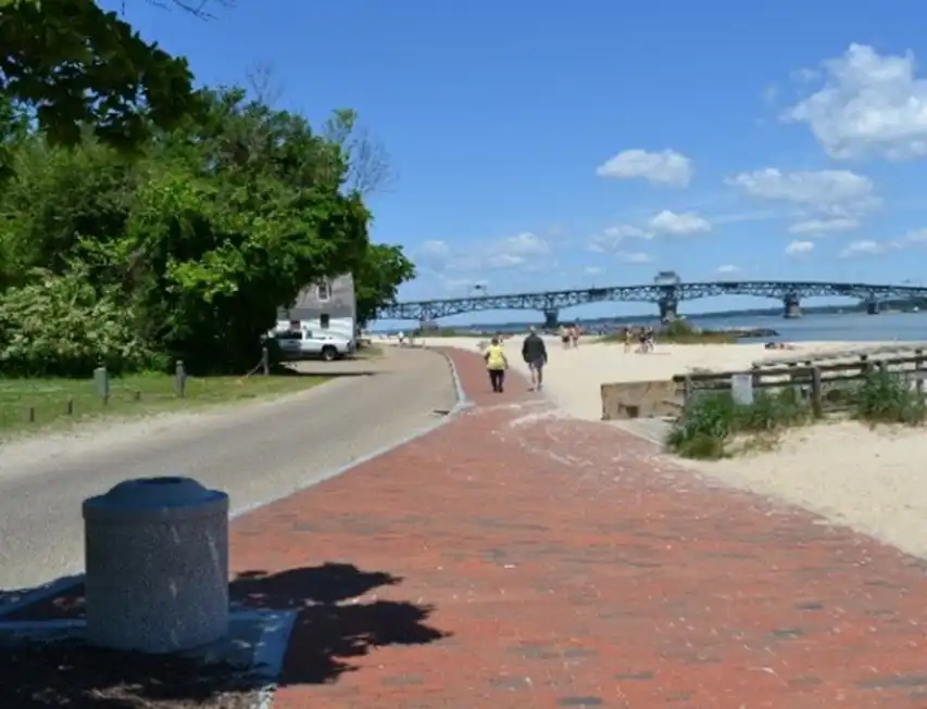 A roadway, brick path, and sandy beach along the Yorktown Waterfront