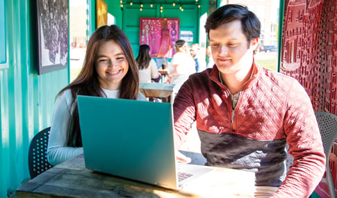 A man and a woman smiling looking at a laptop