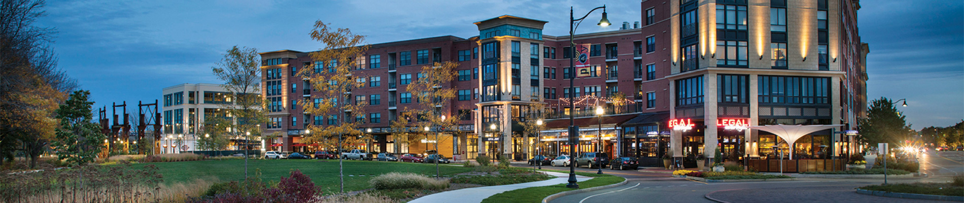 A night shot of a housing complex with street-level restaurants.