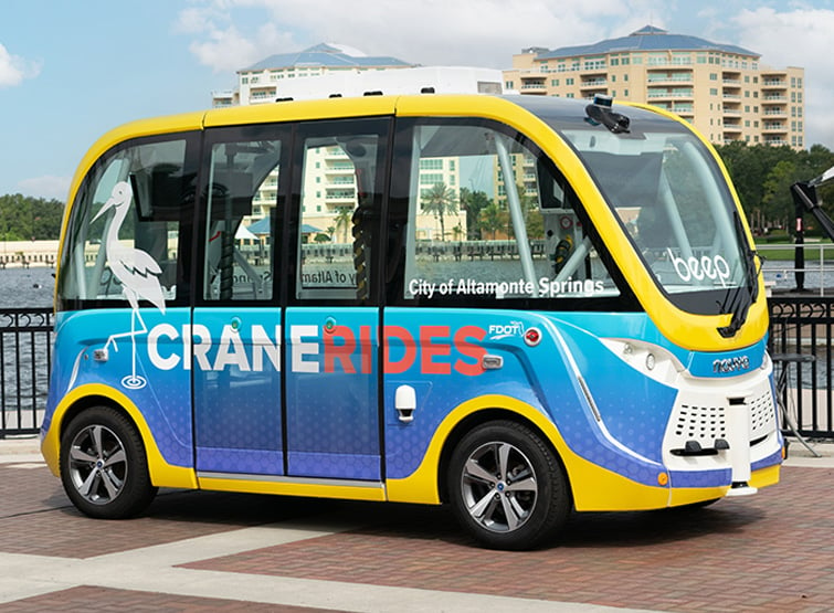 A blue and yellow autonomous vehicle with the words Crane Rides on the side.