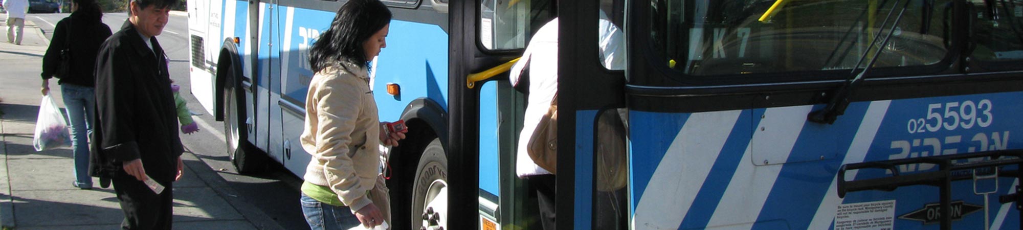 Riders line up to enter the Ride On bus at the bus stop.