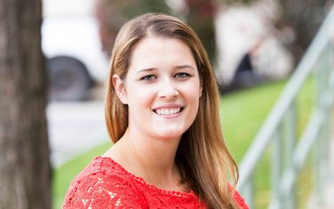 Brianne smiling in red shirt.