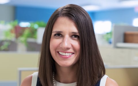 Nadia Boller smiles at the camera wearing a navy blue top and pearls.