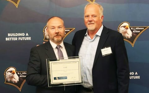 Two men holding an award.