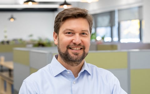 Ryan Prime in an office, wearing a blue shirt and smiling. 