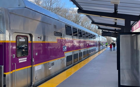 A purple and gray MBTA commuter train at a modern station.