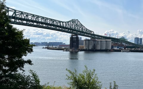 A bridge over water with an industrial plant below it.