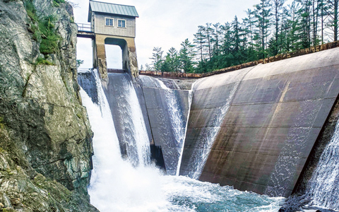 A cement hydropower dam with water spilling over.