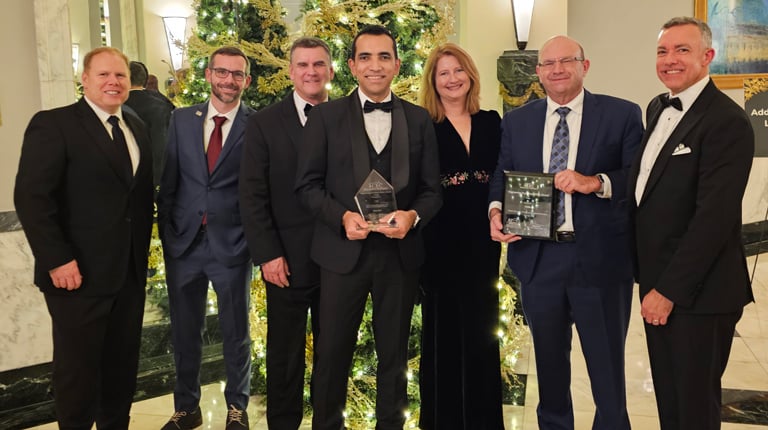 VHBers stand together in front of the Christmas tree with the three awards.