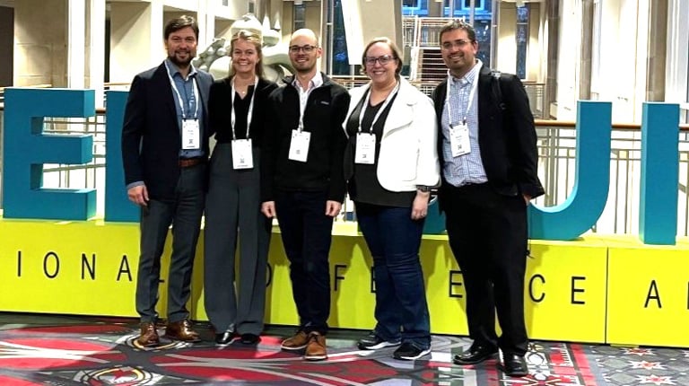 Five VHB employees standing in front of a large Greenbuild sign.