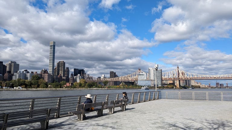 View of East River with people sitting on benches.