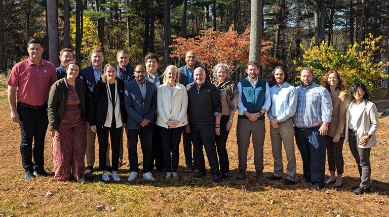 A group of seventeen LEADS participants and facilitators in business casual attire standing outside for a group photo.