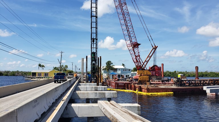 A crane in the water near a bridge.