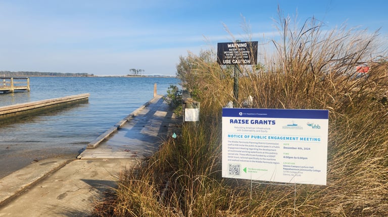 A sign promoting the project at one of the waterfront sites with the water in the background.