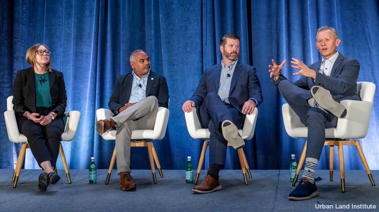 Four panelists sitting on a stage engaged in a discussion at a conference.