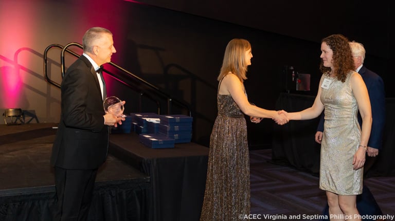 Lauren Blackburn shakes hands on stage and accepts the Virginia ACEC award.