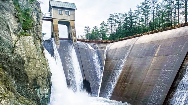 A cement hydropower dam with water spilling over.