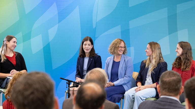 Five women on high stools engaged in a panel discussion.
