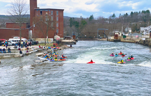 Kayakers and bystanders enjoying whitewater in a river.