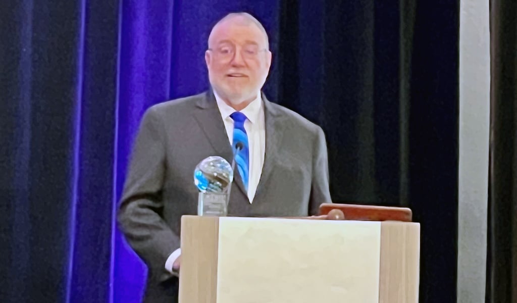 Bob stands at a podium to receive his award.